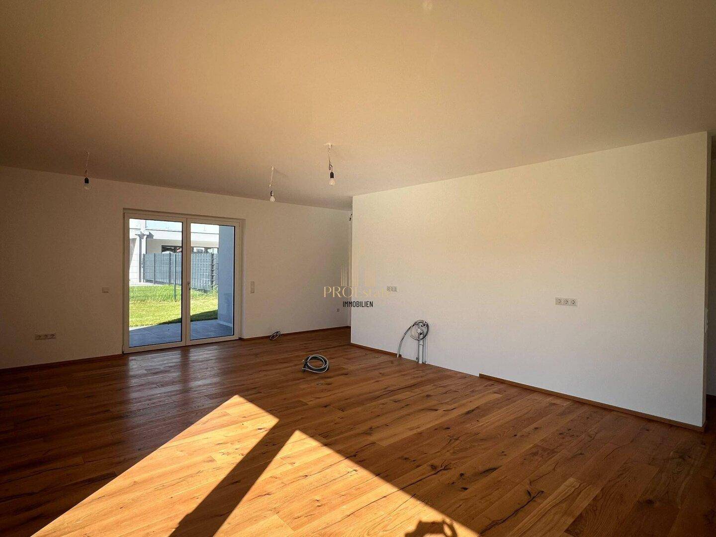 Helles Wohnzimmer mit Holzdielenboden und großem Schiebefenster zum Garten.