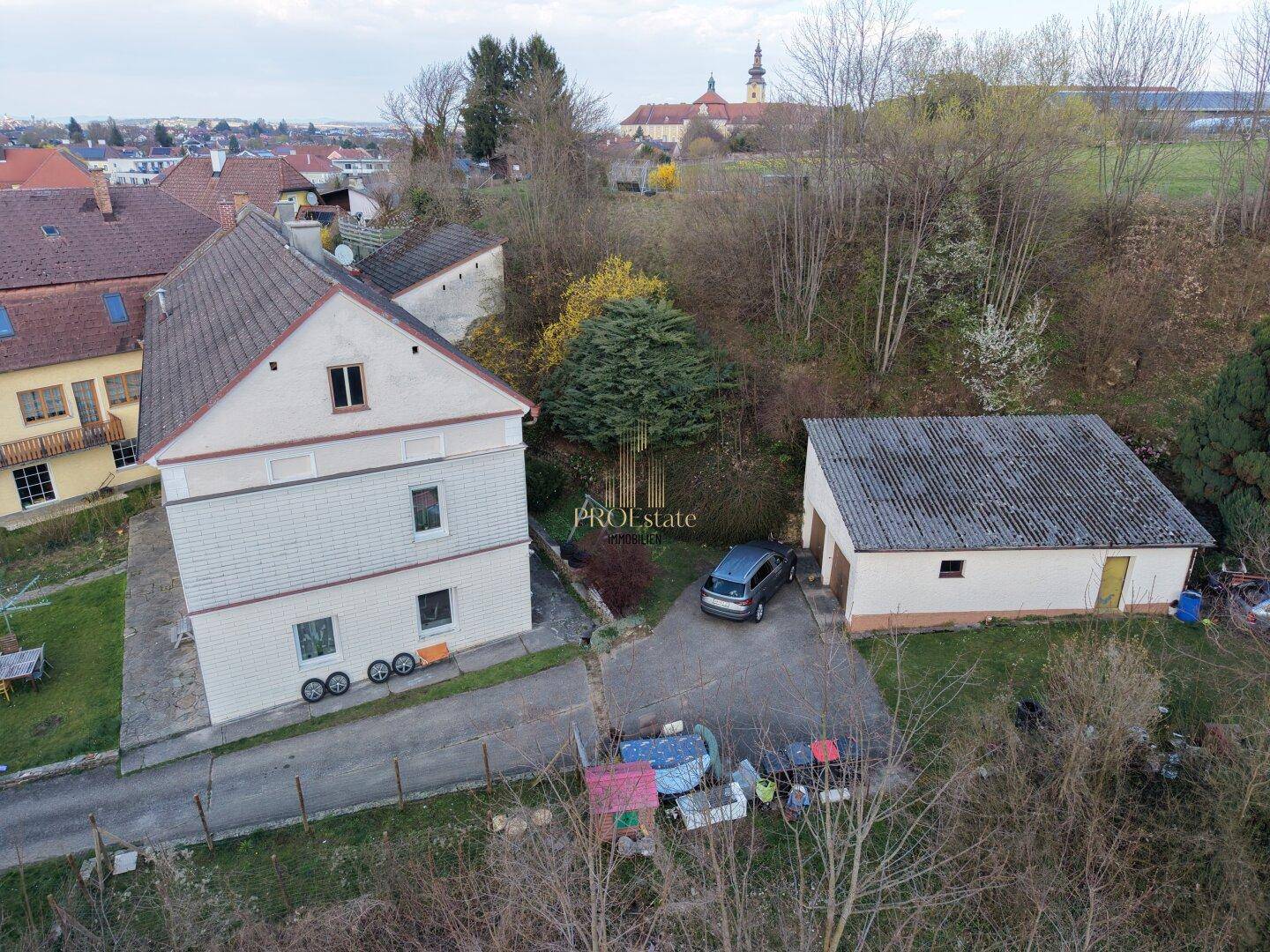 Luftaufnahme des Anwesens mit Hauptgebäude, Garage und umliegender Natur.