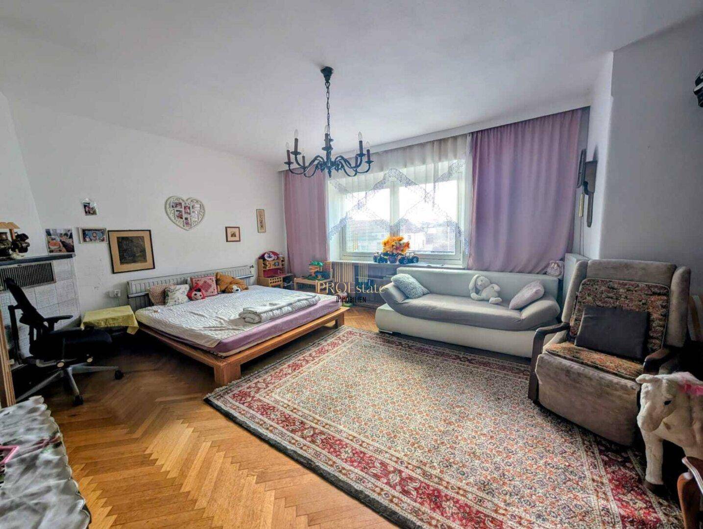 Geräumiges Schlafzimmer mit Parkettboden, großem Bett und Sofa.