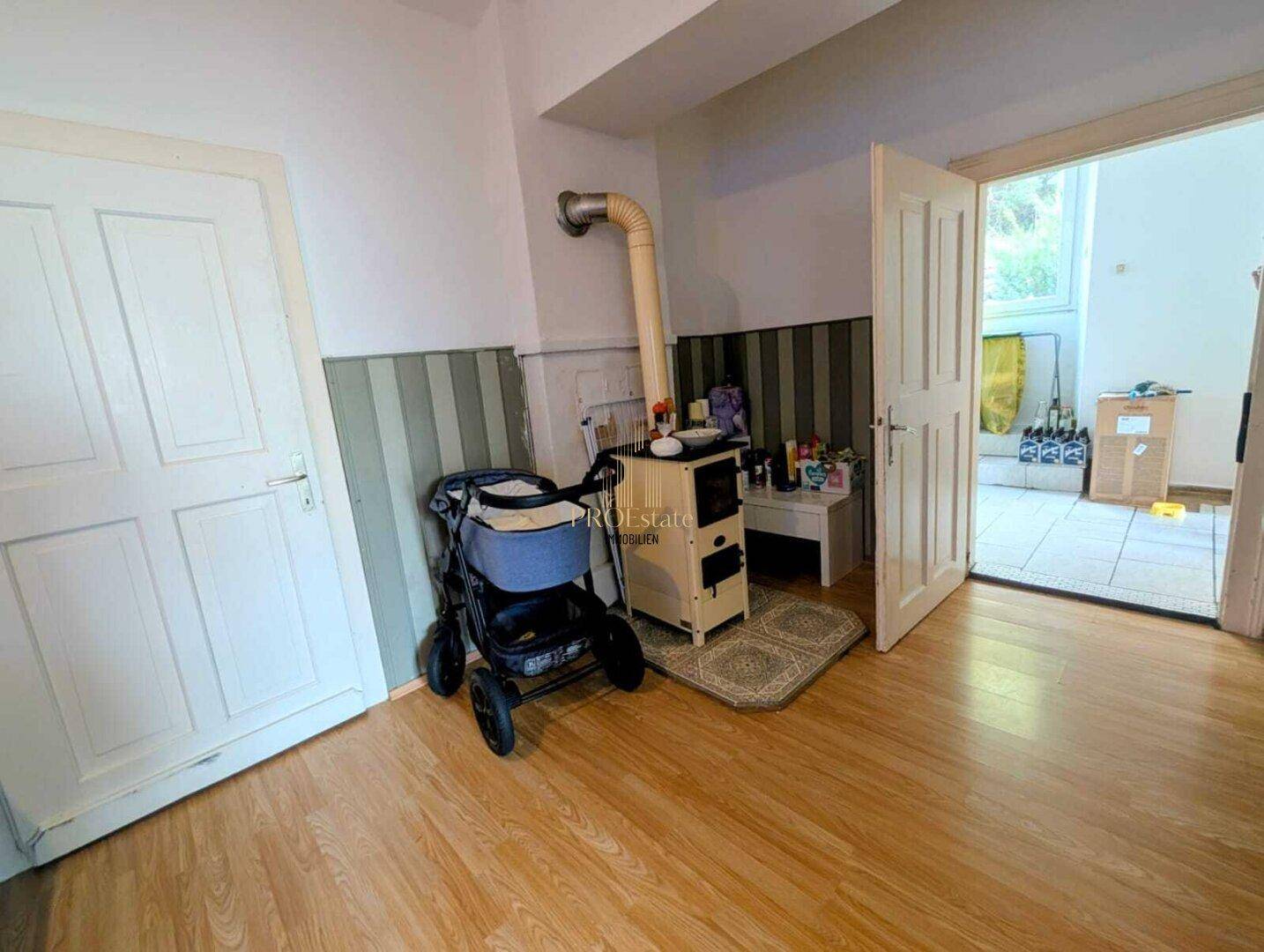 Eingangsbereich oder Flur mit einem Holzofen und Zugang zu einem weiteren Raum.