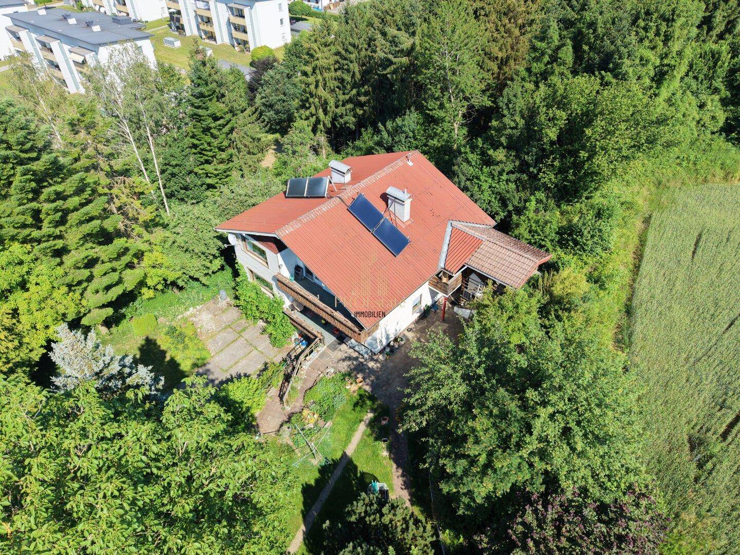 Luftaufnahme des Hauses mit rotem Ziegeldach und Solarpaneelen, umgeben von viel Grün.
