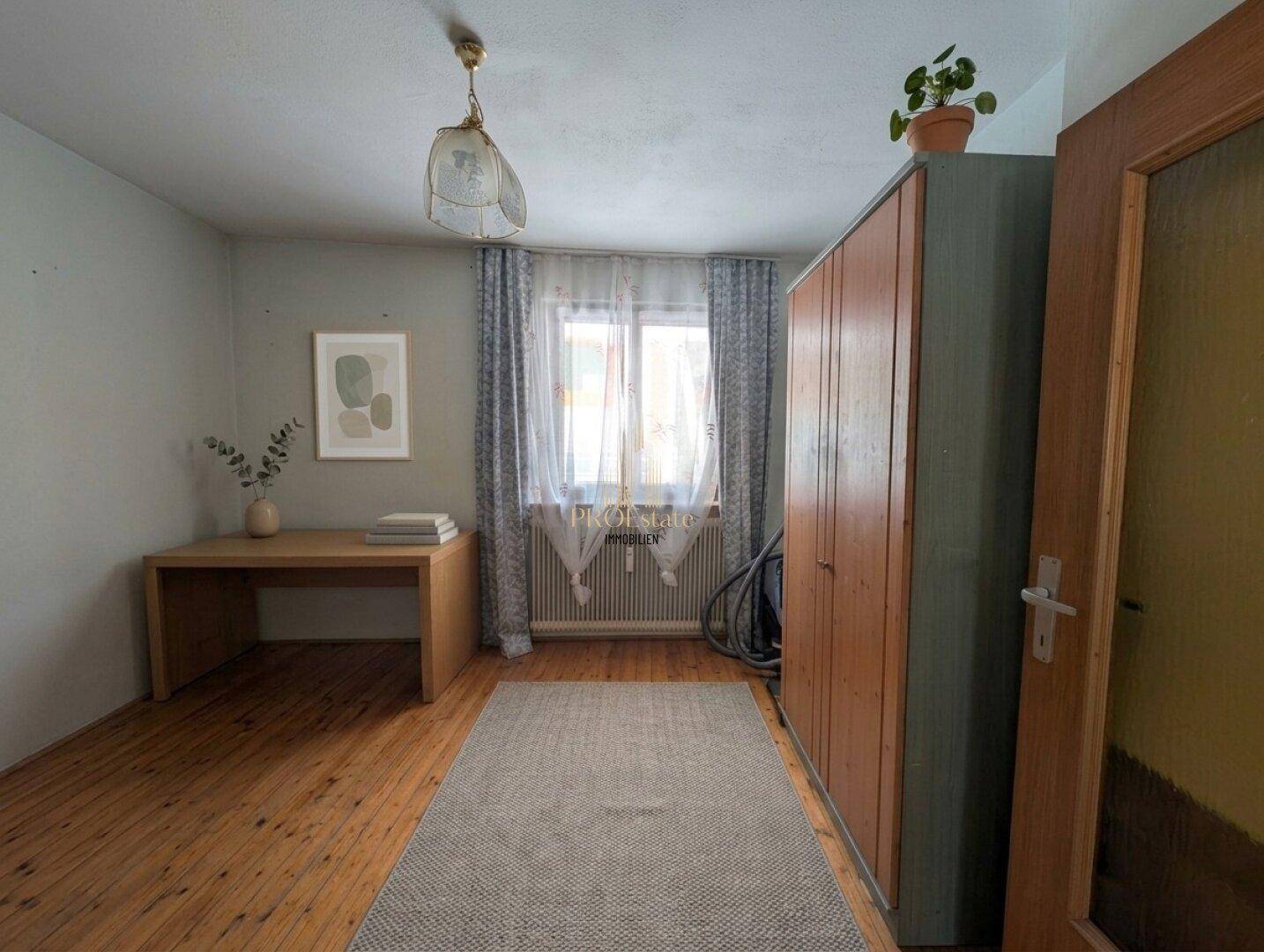 Helles Arbeitszimmer mit Holzfußboden, Schreibtisch und einem Fenster mit Vorhängen.