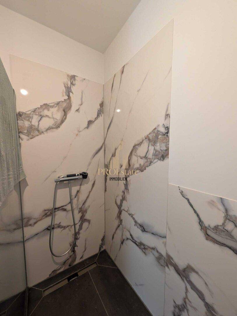 Moderne Dusche mit großformatigen Marmorfliesen und minimalistischem Design.