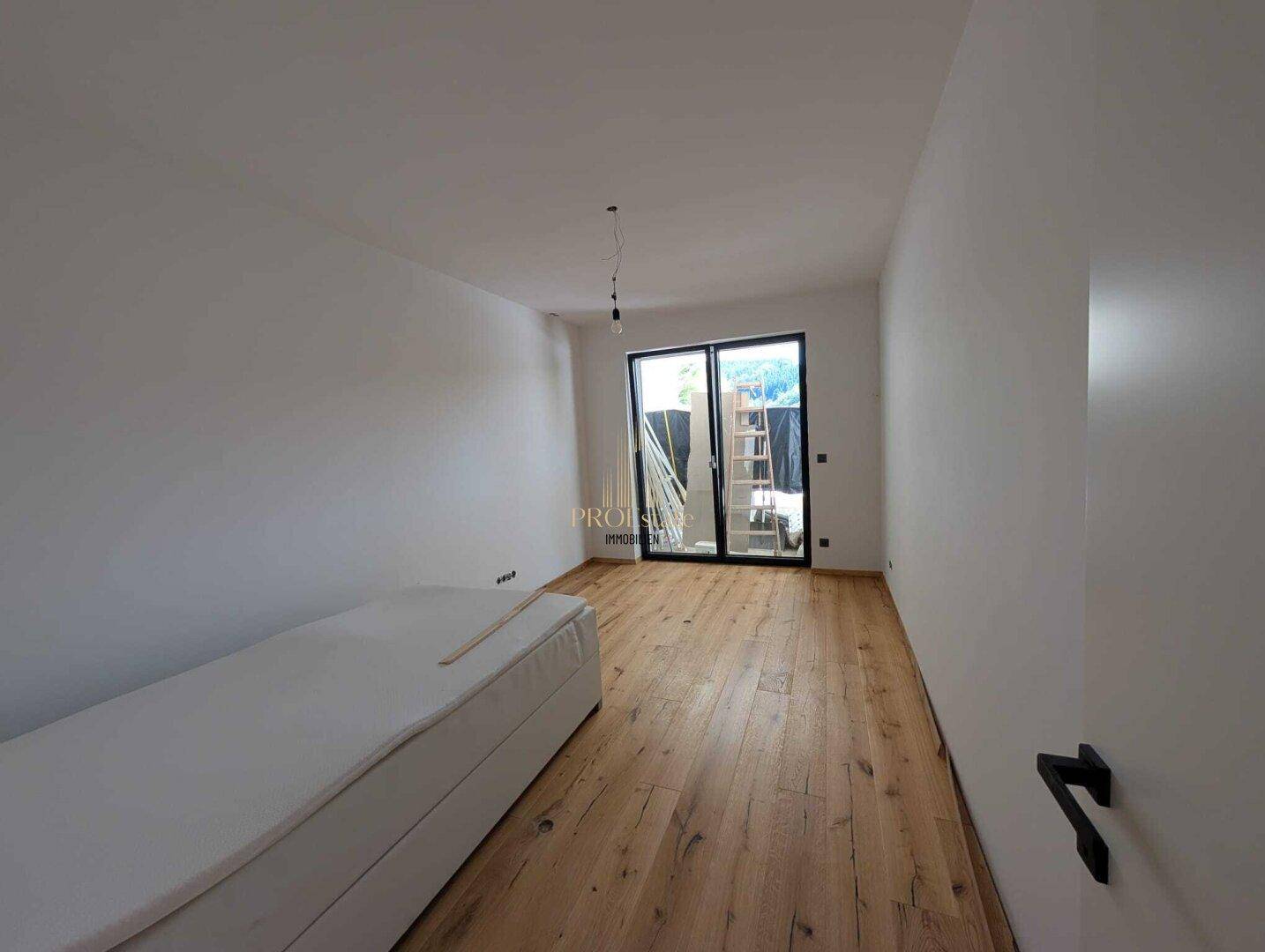 Lichtdurchflutetes Zimmer mit Holzboden und Zugang zu einem Außenbereich.