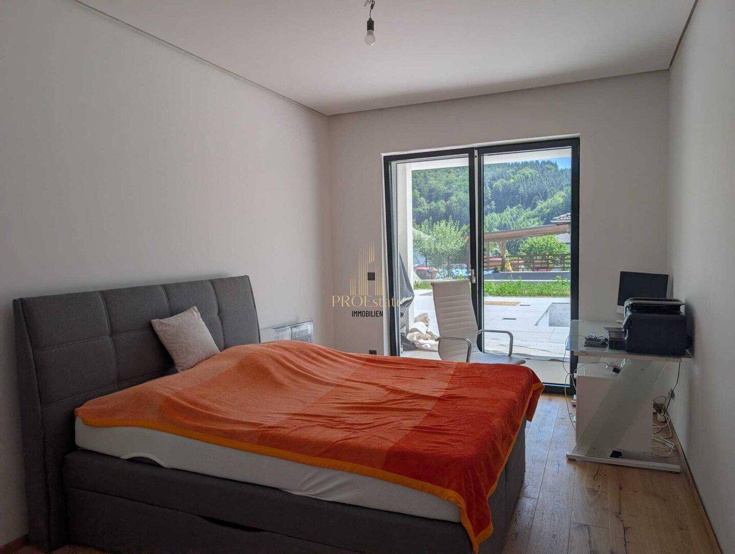 Gemütliches Schlafzimmer mit Doppelbett, Holzboden und großem Fenster mit Blick ins Grüne.