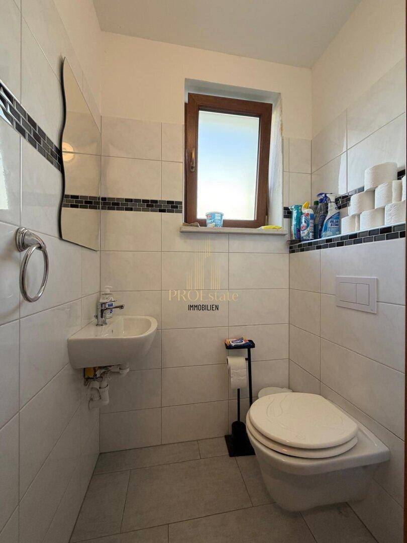 Modernes Gäste-WC mit Wand-WC, kleinem Waschbecken und Fenster.