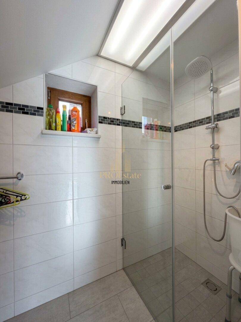 Modernes Badezimmer mit begehbarer Dusche und Dachfenster.