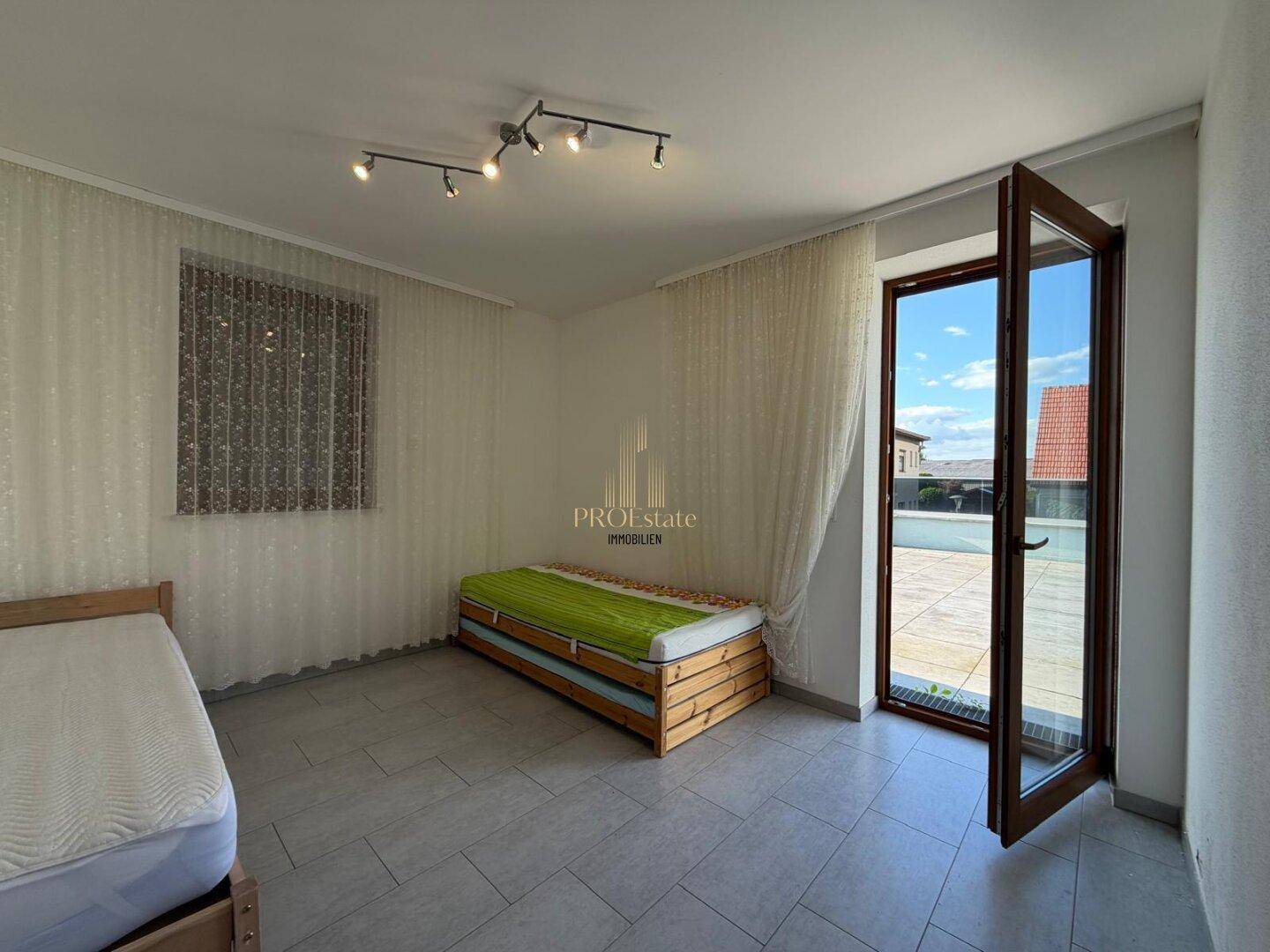 Schlafzimmer mit Fliesenboden und Zugang zur Dachterrasse.