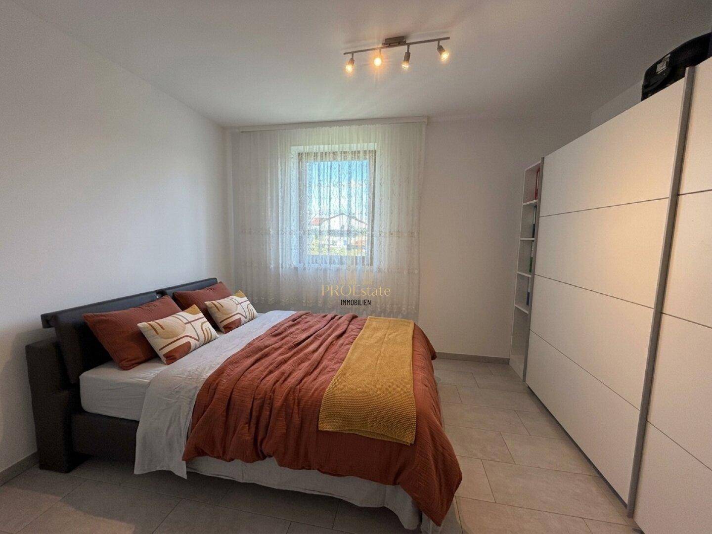 Gemütliches Schlafzimmer mit Doppelbett, Kleiderschrank und Fenster.