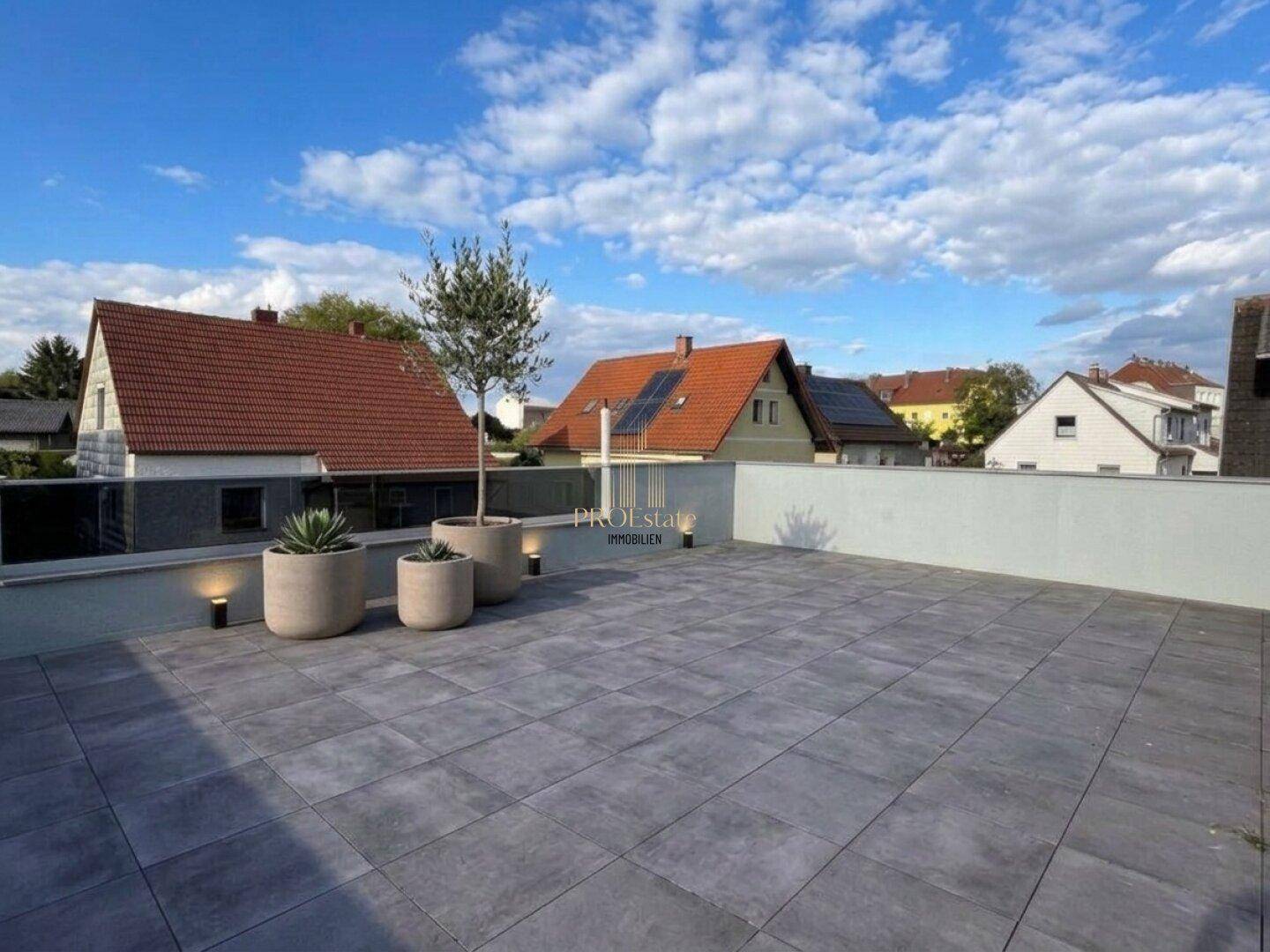 Geräumige Dachterrasse mit Fliesenboden und Blick auf die Nachbarschaft.