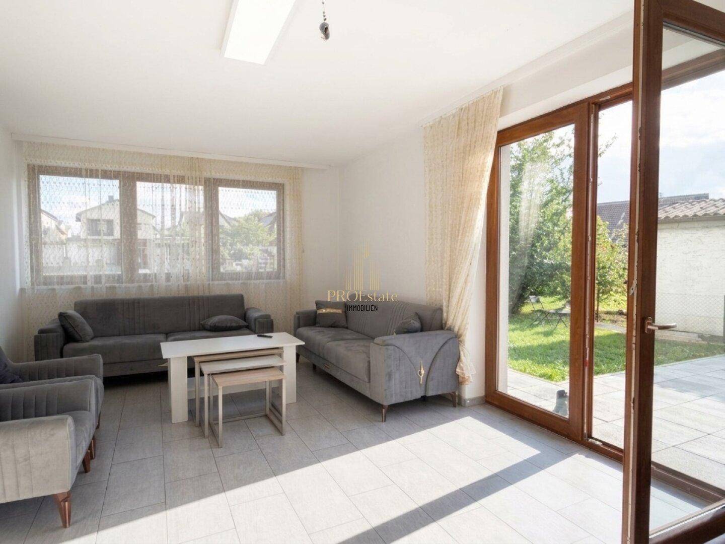 Helles Wohnzimmer mit Fliesenboden und Zugang zur Terrasse.
