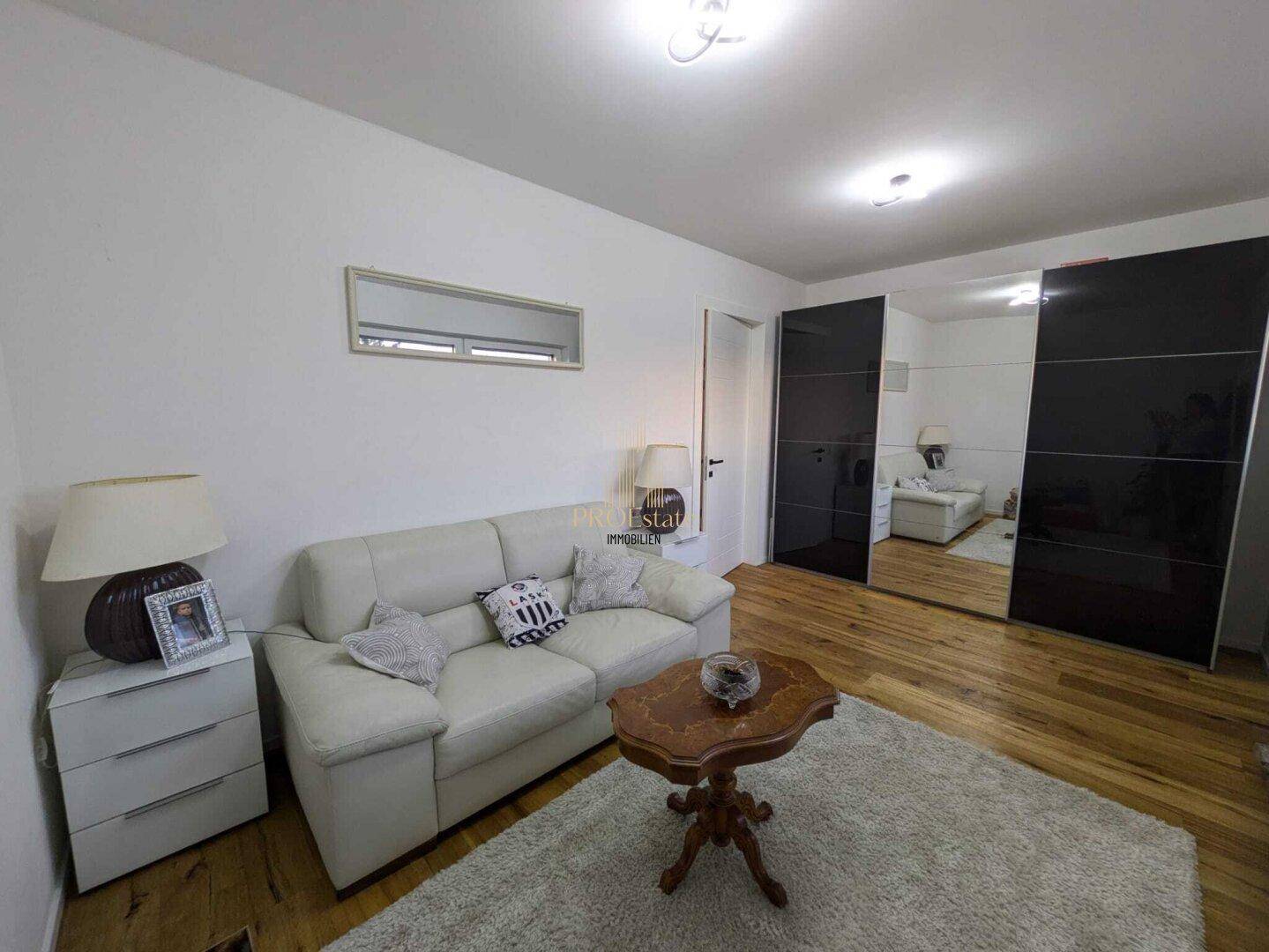 Gemütliches Zimmer mit Sofa, Couchtisch und großen Spiegelschränken für viel Stauraum.