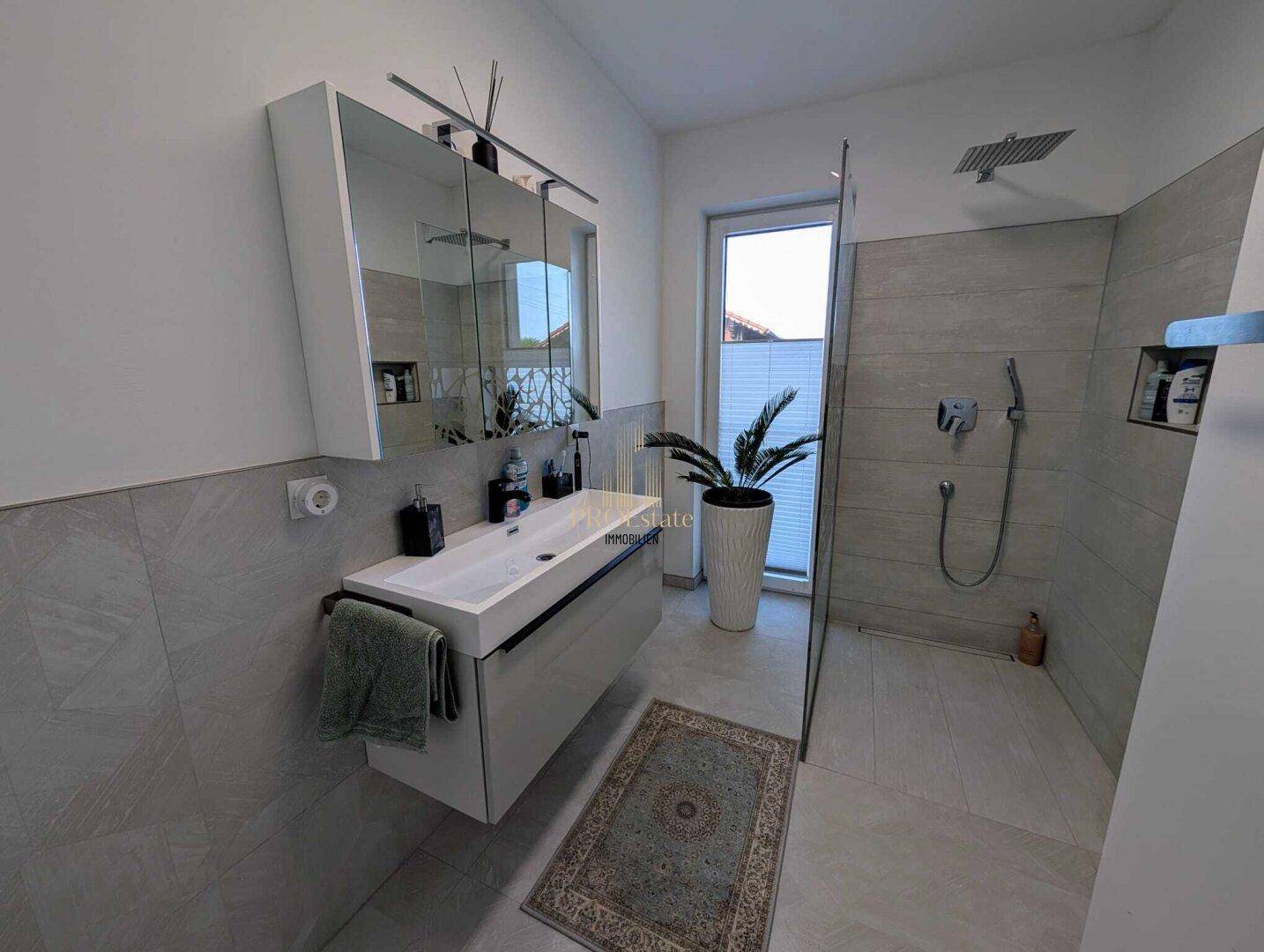 Modernes Badezimmer mit begehbarer Dusche, stilvollem Waschtisch und Fenster für Tageslicht.