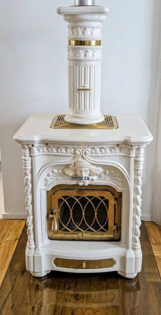 Prunkvoller weißer Kachelofen mit goldenen Akzenten, ein traditionelles Heizelement.