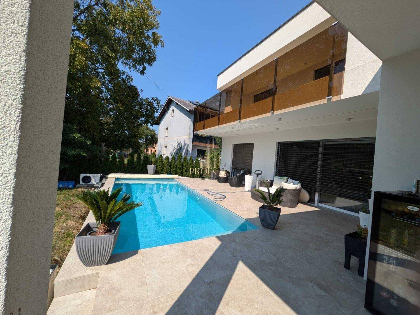 Moderner Außenbereich mit Swimmingpool, Liegeflächen und stilvollen Gartenmöbeln.