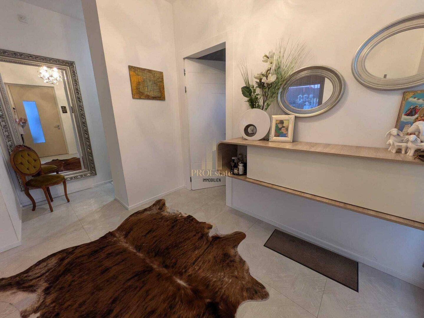 Heller Eingangsbereich mit großem Spiegel, moderner Konsole und einem dekorativen Teppich.