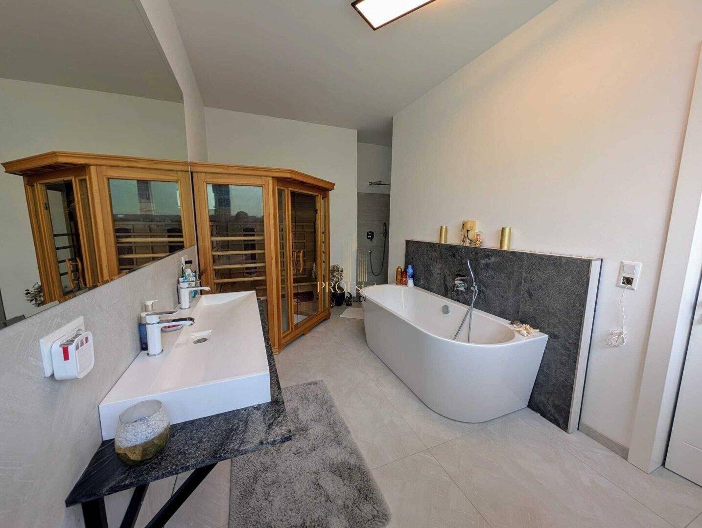 Luxuriöses Badezimmer mit freistehender Badewanne, modernem Waschtisch und integrierter Sauna.