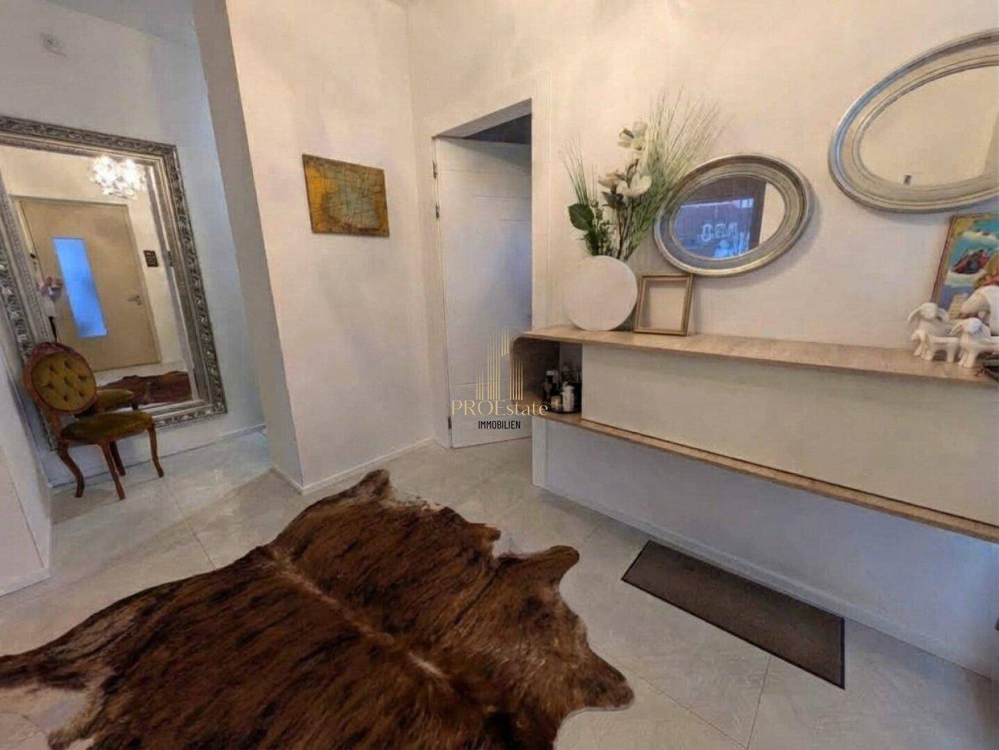 Helle Diele mit Fliesenboden, großem Spiegel und moderner Konsole als Blickfang.