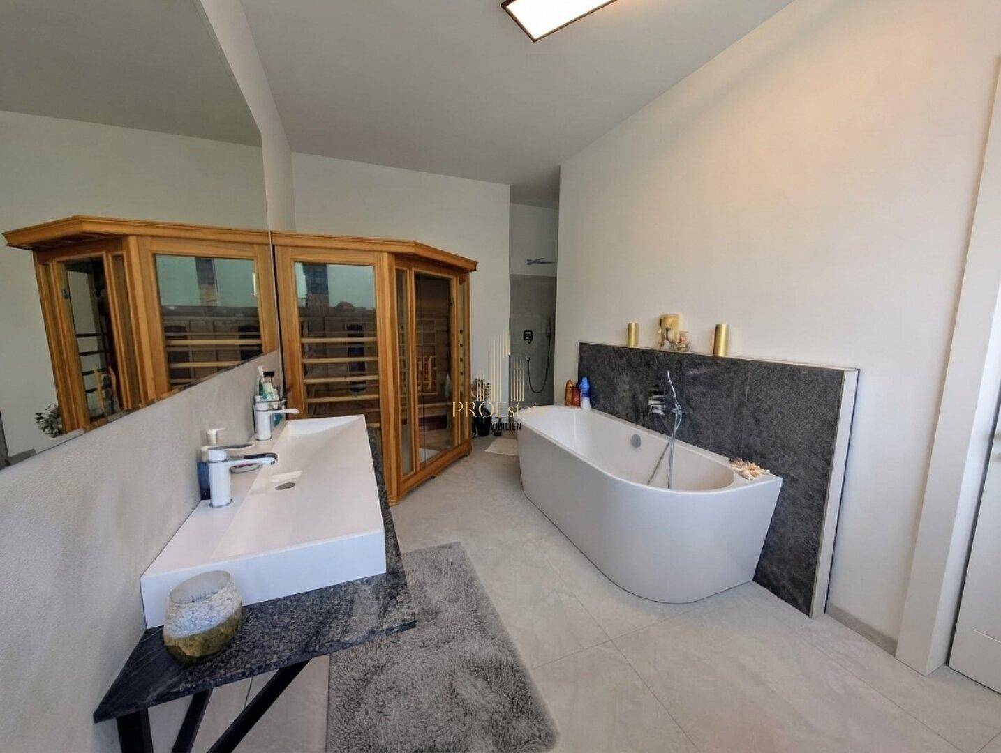 Modernes Badezimmer mit freistehender Badewanne, Doppelwaschbecken und integrierter Sauna.