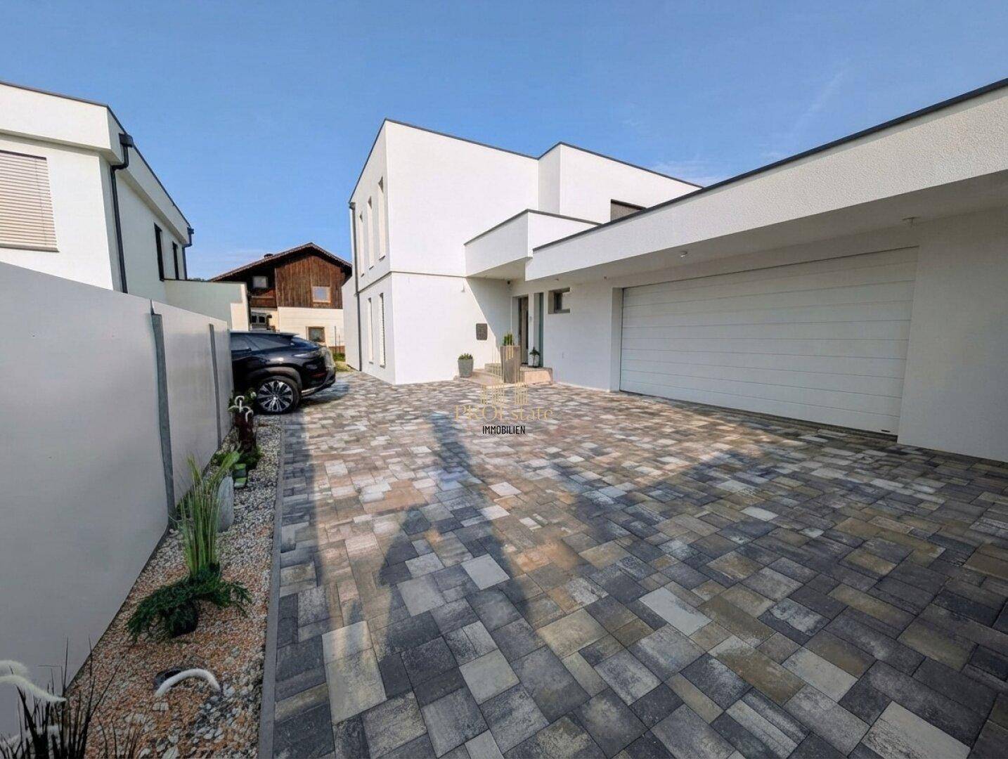 Modernes Einfamilienhaus mit gepflasterter Einfahrt und integrierter Doppelgarage.