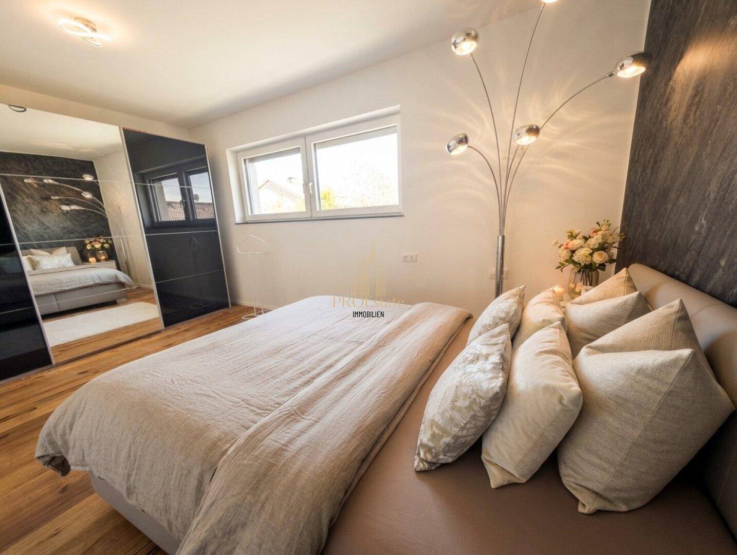 Helles Schlafzimmer mit Holzboden, großem Bett, Spiegelschrank und moderner Stehlampe, die für zusätzliche Beleuchtung sorgt.