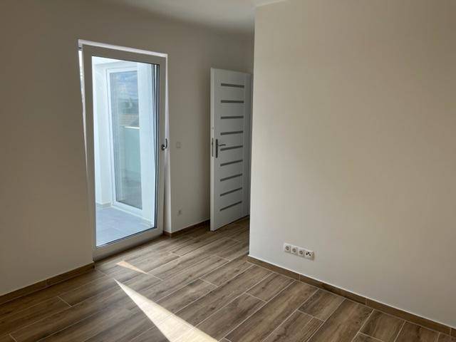 Schlafzimmer mit Holzoptik-Fliesenboden und Zugang zu einem Außenbereich, bietet viel natürliches Licht.