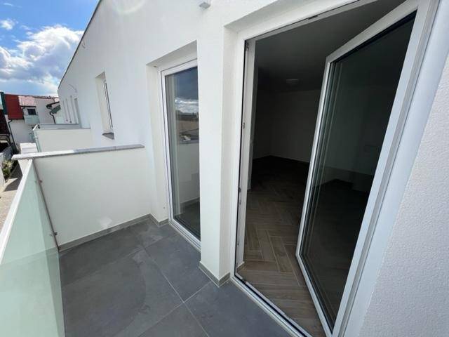 Moderner Balkon mit Fliesenboden und Glasgeländer, bietet einen angenehmen Außenbereich zum Entspannen.