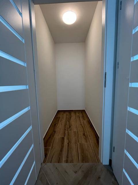 Praktischer Abstellraum mit Holzoptik-Fliesenboden und Deckenleuchte, ideal für zusätzlichen Stauraum.