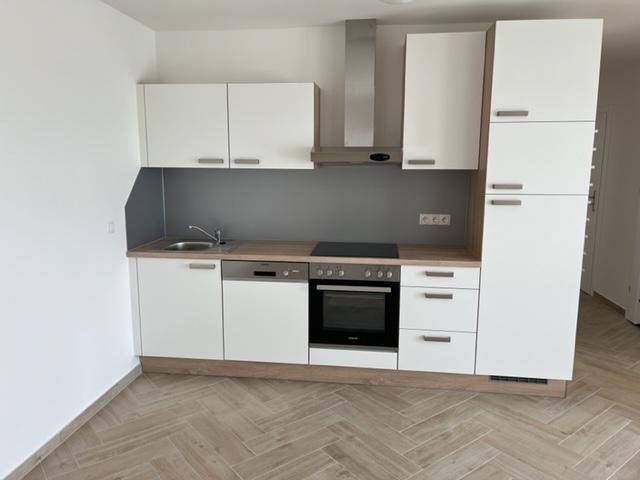 Moderne Einbauküche mit weißen Fronten, Holz-Arbeitsplatte und integrierten Geräten, bereit zur Nutzung.