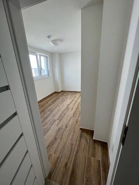 Helles Schlafzimmer mit Holzoptik-Fliesenboden und Fenster, das eine angenehme Wohnatmosphäre schafft.