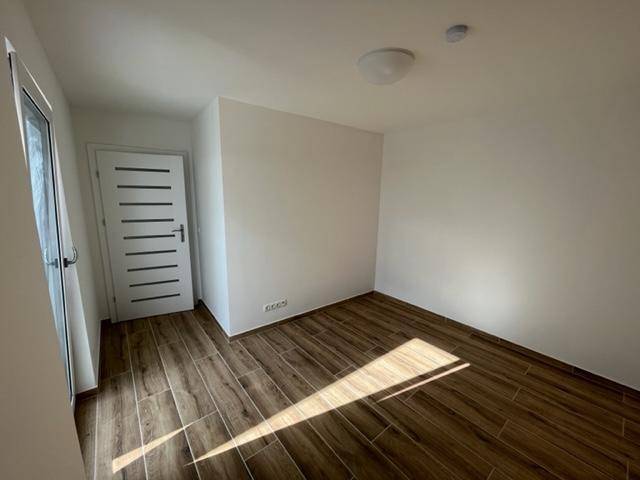 Helles Schlafzimmer mit Holzoptik-Fliesenboden und schlichter Gestaltung, ideal für individuelle Einrichtung.