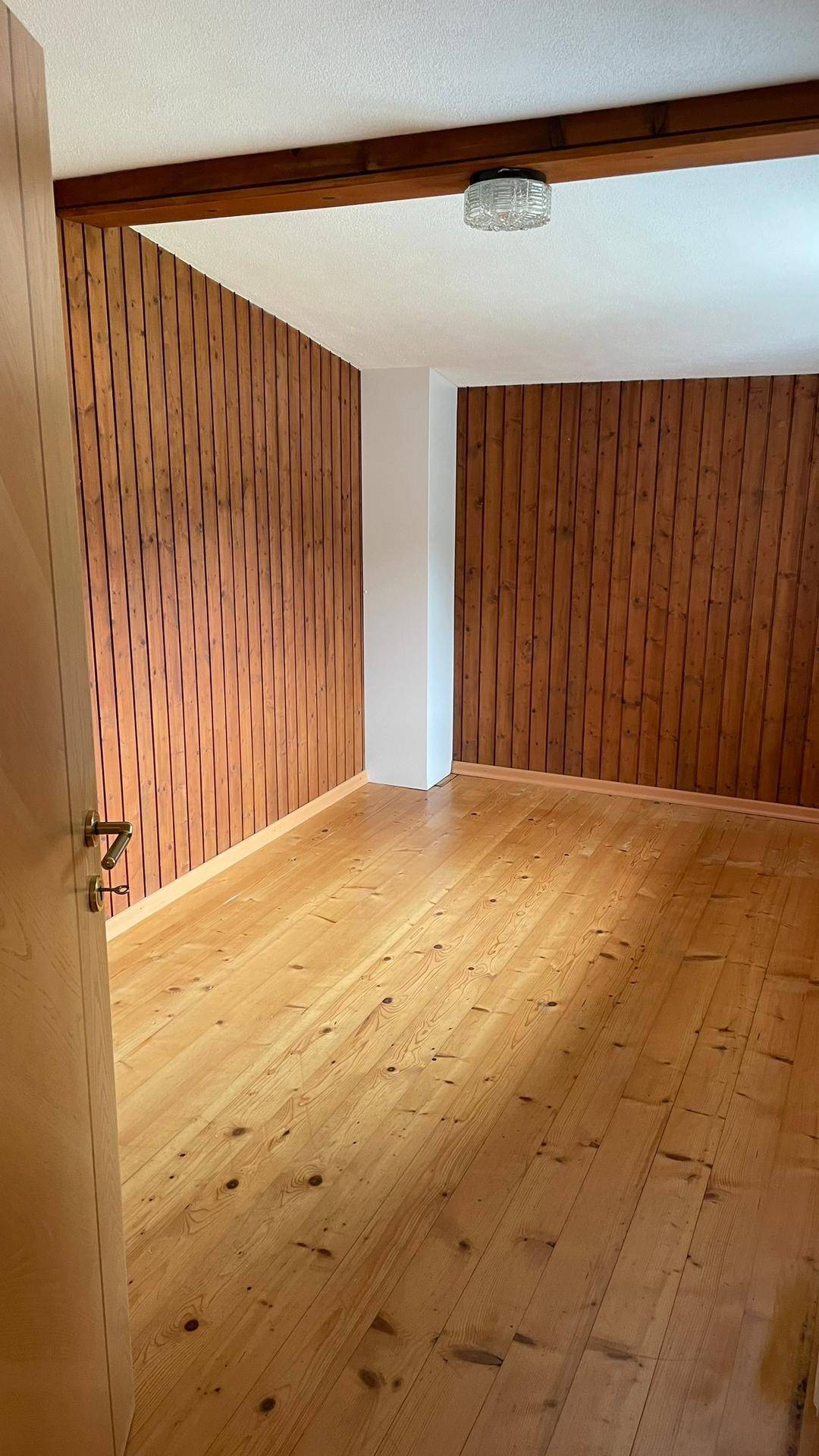 Gemütliches Zimmer mit Holzwänden und Dielenboden, ideal für ein Schlafzimmer.
