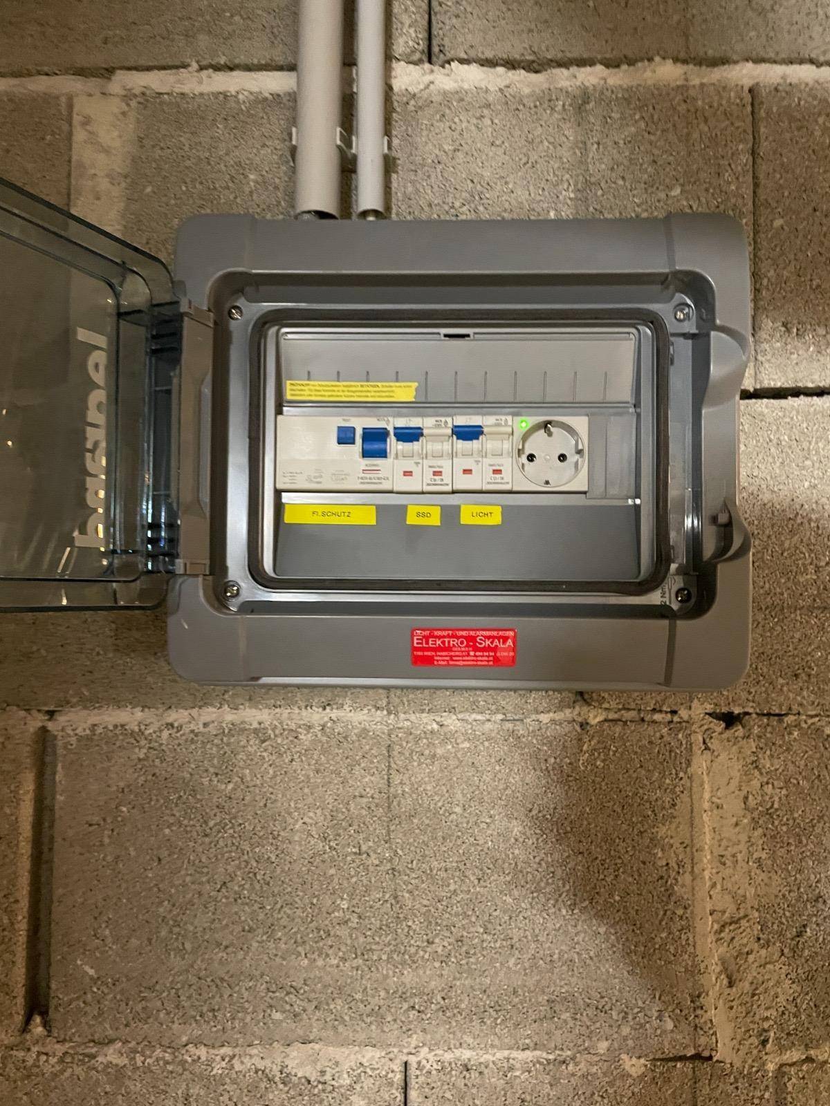Sicherungskasten an einer Betonblockwand, der die elektrische Installation des Gebäudes zeigt.