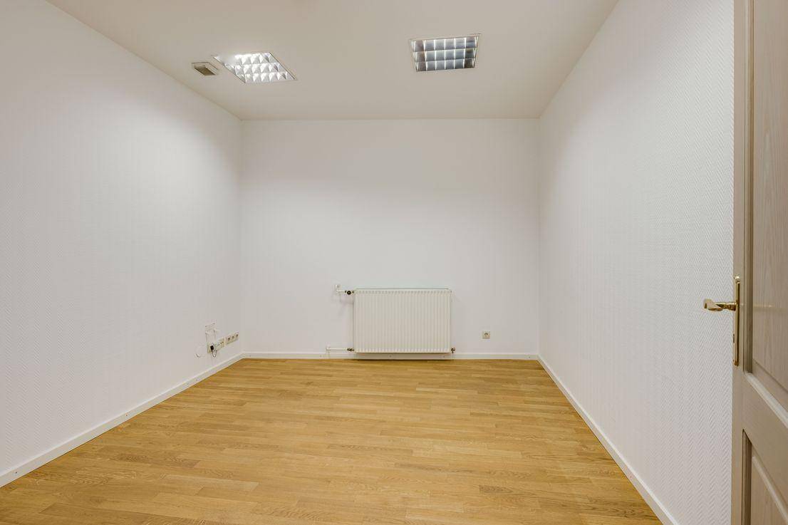 Kleiner, heller Raum mit Holzfußboden, weißer Tapete und Deckenleuchten, ideal als Arbeitszimmer oder Schlafzimmer.
