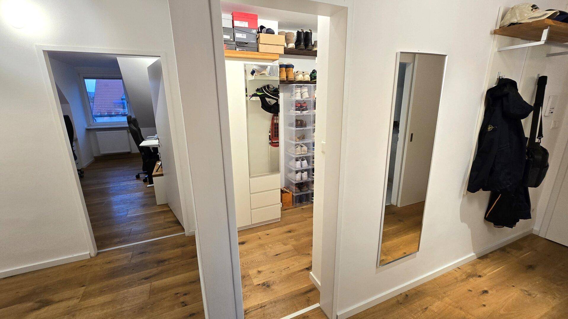 Heller Flur mit Holzboden und Zugang zu einem begehbaren Kleiderschrank und weiteren Räumen.