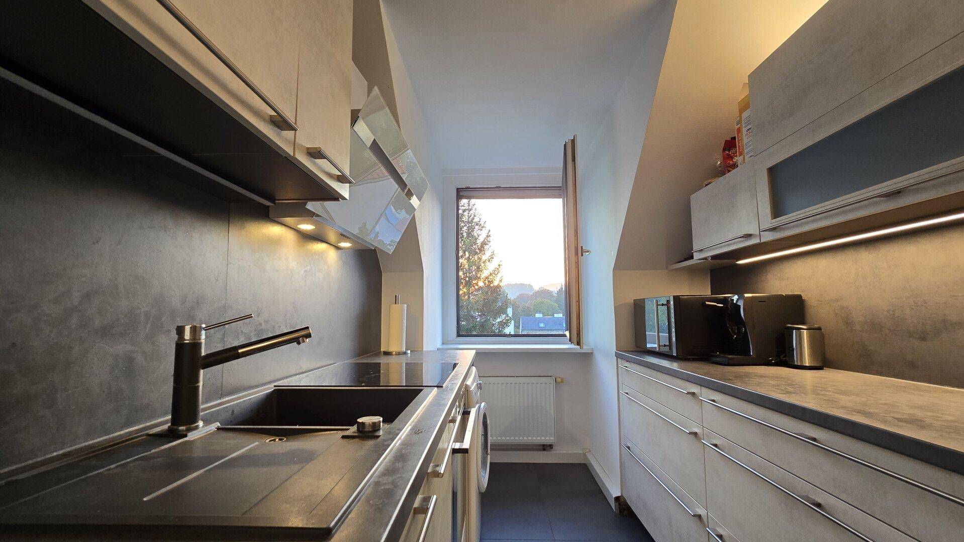 Moderne Küche mit Fenster, Spülbecken und integrierten Geräten im Dachgeschoss.
