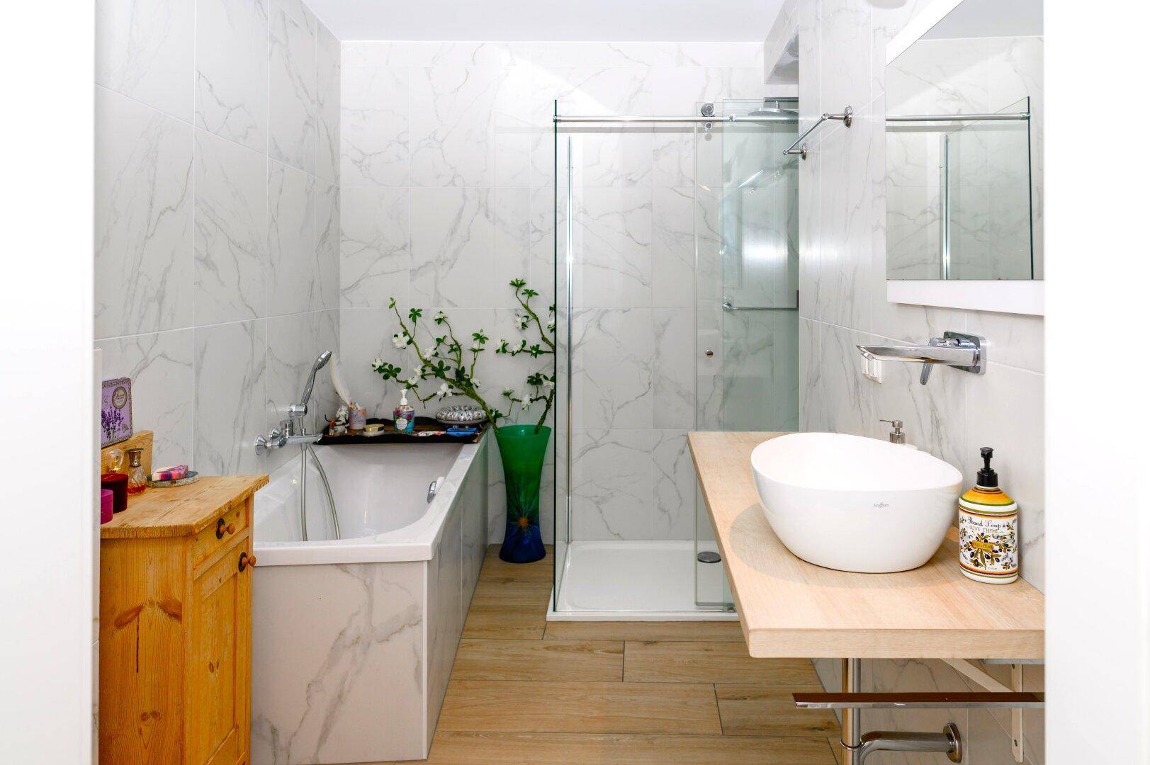 Modernes Badezimmer mit Badewanne, begehbarer Dusche und Einzelwaschbecken auf Holzplatte.