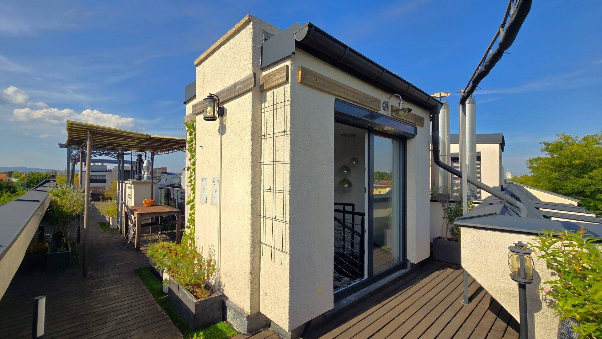 Zugang zur Wohnung von der Dachterrasse mit Holzboden und Blick auf die Umgebung.