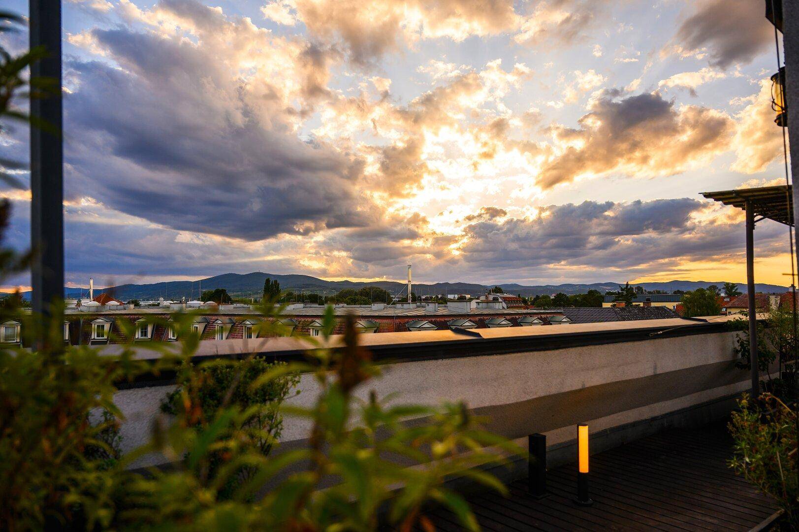Dachterrasse bei Sonnenuntergang mit malerischem Himmel und weitem Blick über die Landschaft.