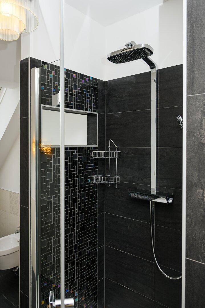 Moderne Duschkabine mit Regendusche und dunklen Mosaikfliesen.