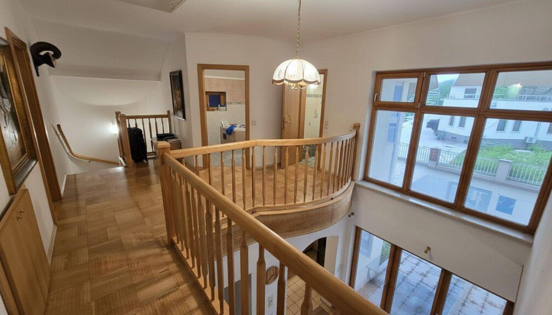 Heller Flur im Obergeschoss mit Holzgeländer und Blick auf den unteren Wohnbereich.