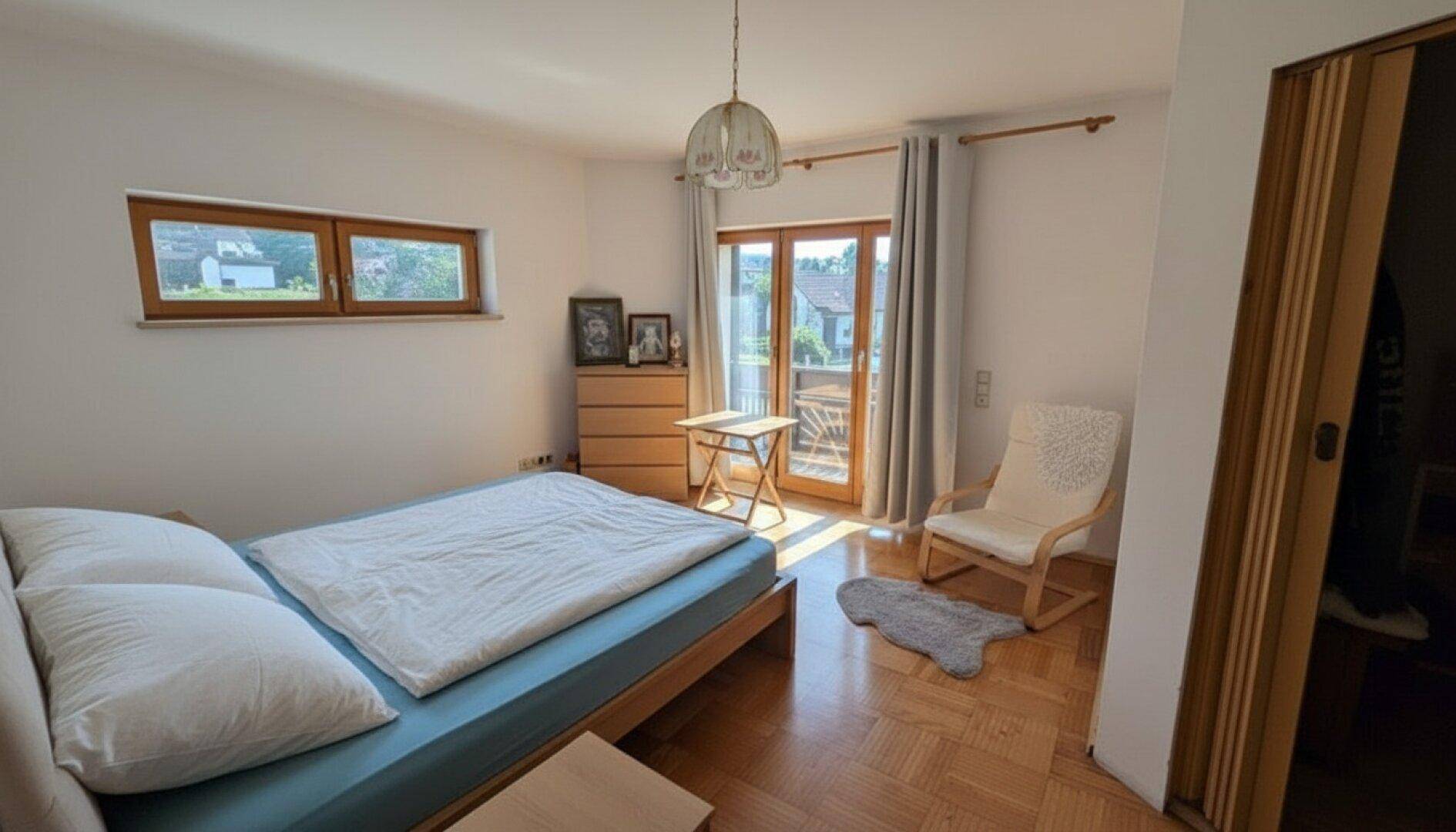 Schlafzimmer mit Parkettboden, Zugang zum Balkon und einem bequemen Doppelbett.