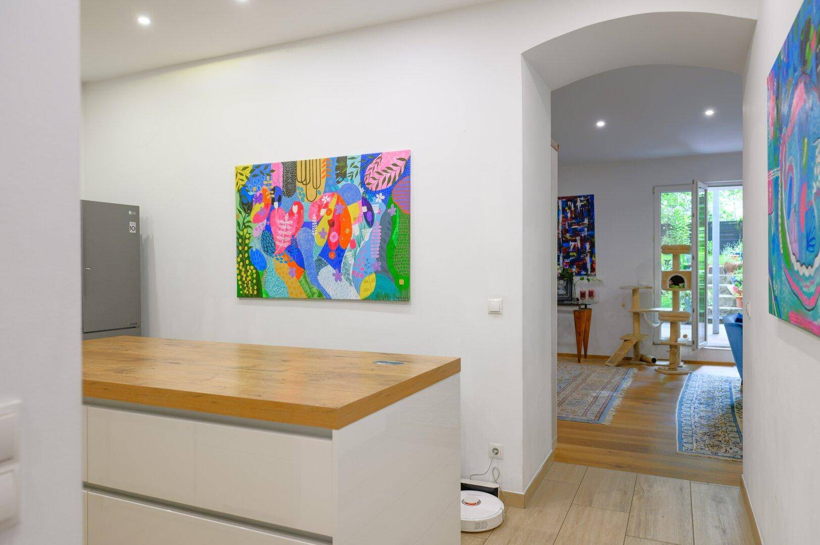 Heller Flur mit farbenfrohem Kunstwerk und Blick in den offenen Wohnbereich.
