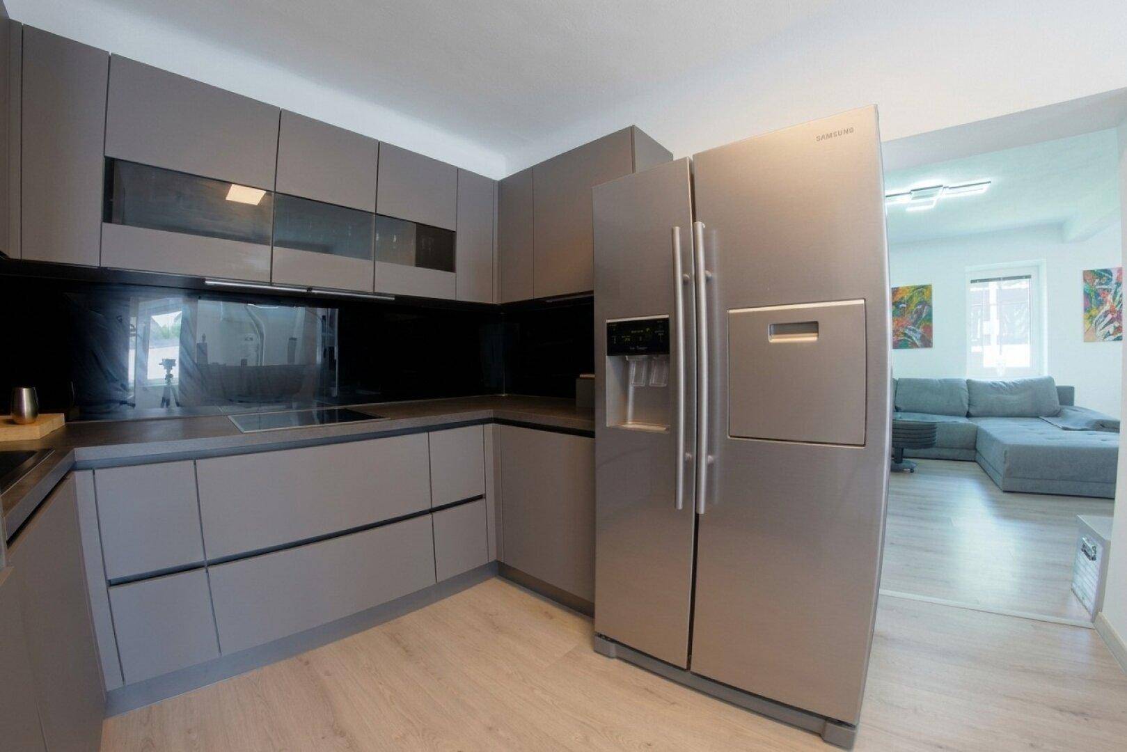Moderne Küche mit grauen Schränken, Induktionskochfeld und großem Kühlschrank.