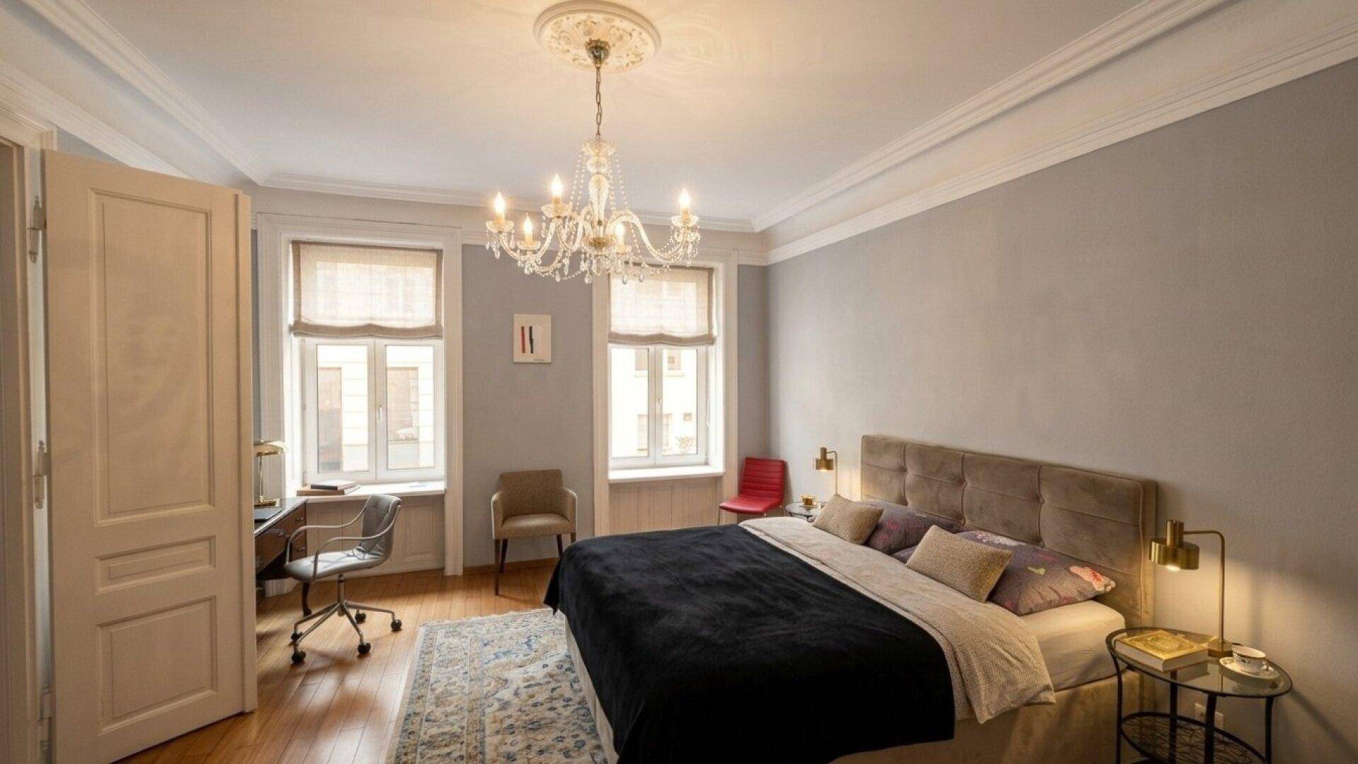 Elegantes Schlafzimmer mit Holzboden, Kronleuchter und Stuckdecke.