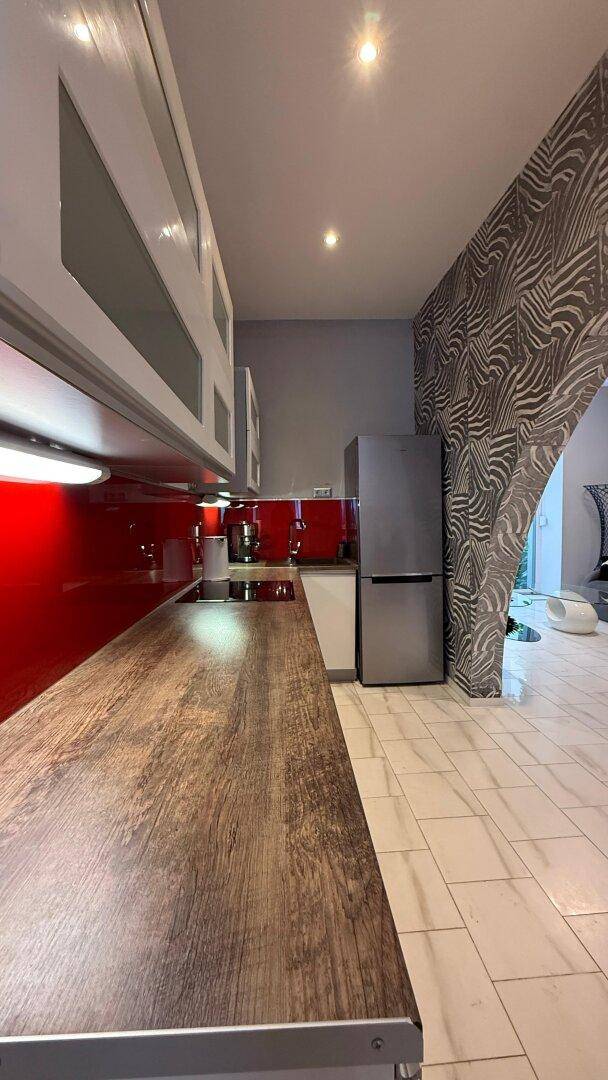 Moderne Küche mit Holz-Arbeitsplatte, roten Akzenten und integriertem Kühlschrank.