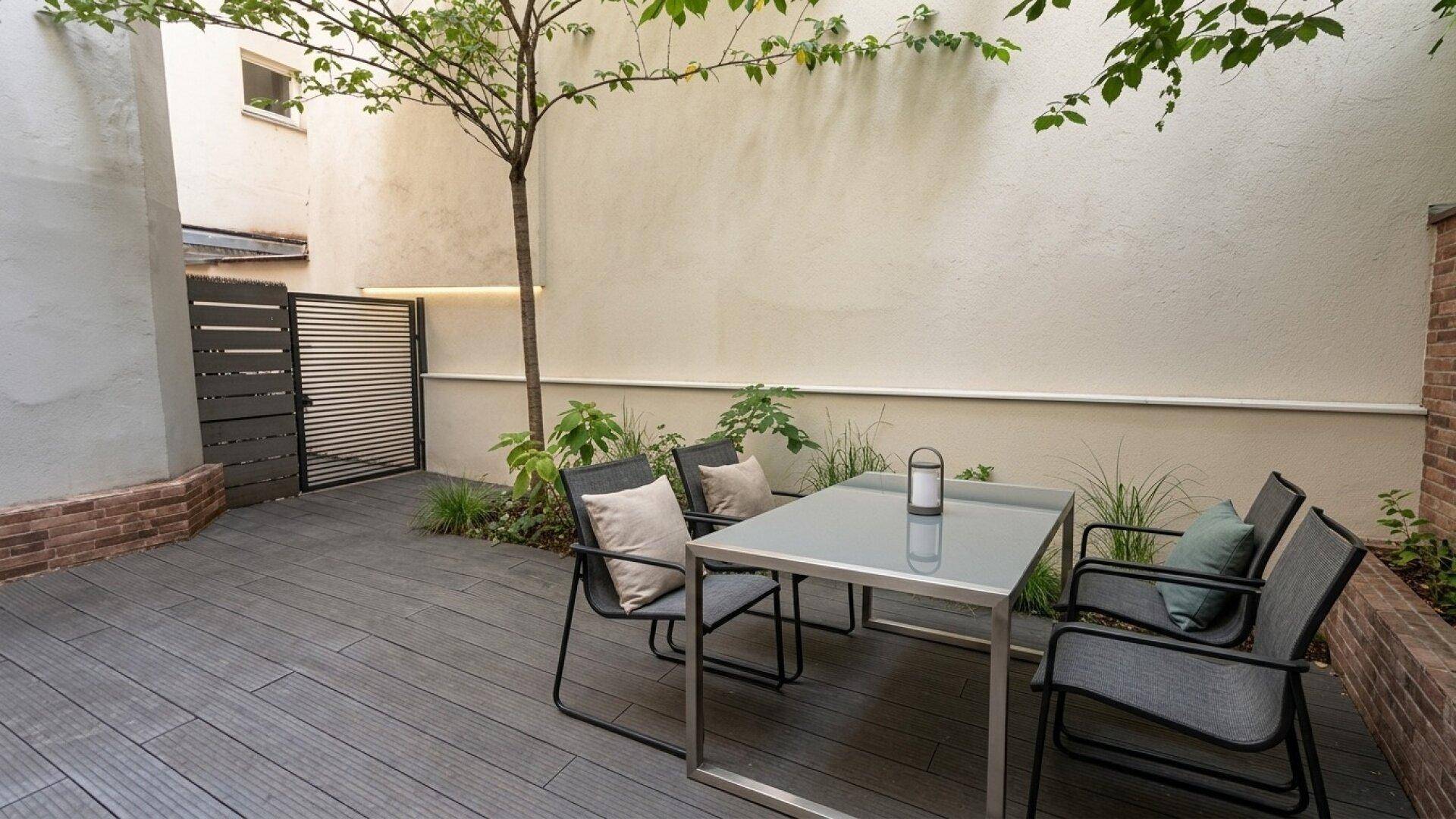 Ruhige Terrasse mit Holzdeck, modernem Sitzbereich und grüner Bepflanzung.