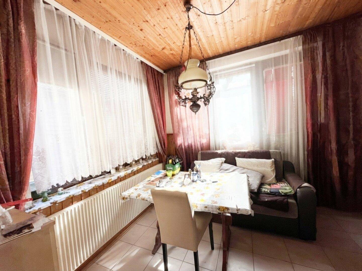 Heller Essbereich mit Holzdecke, Fliesenboden und großzügigen Fenstern, ideal für Mahlzeiten.