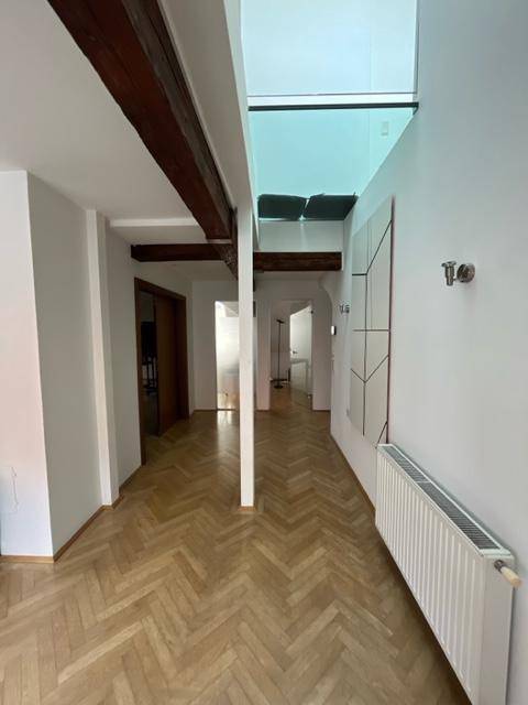 Langer Flur mit Fischgrätparkett, weißen Wänden und einem modernen Glasdach, das den Raum erhellt.