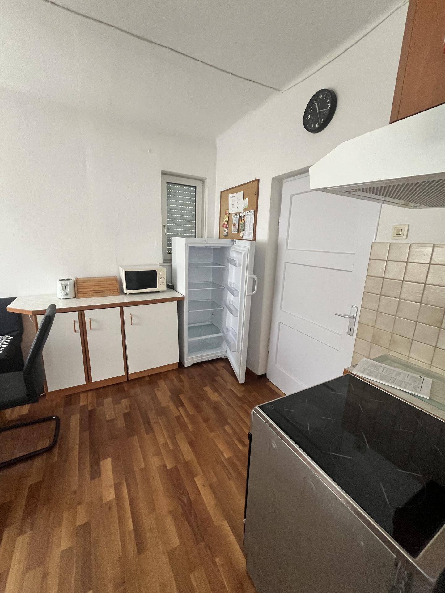 Funktionale Küche mit Laminatboden, Kühlschrank und Mikrowelle, bietet ausreichend Stauraum.